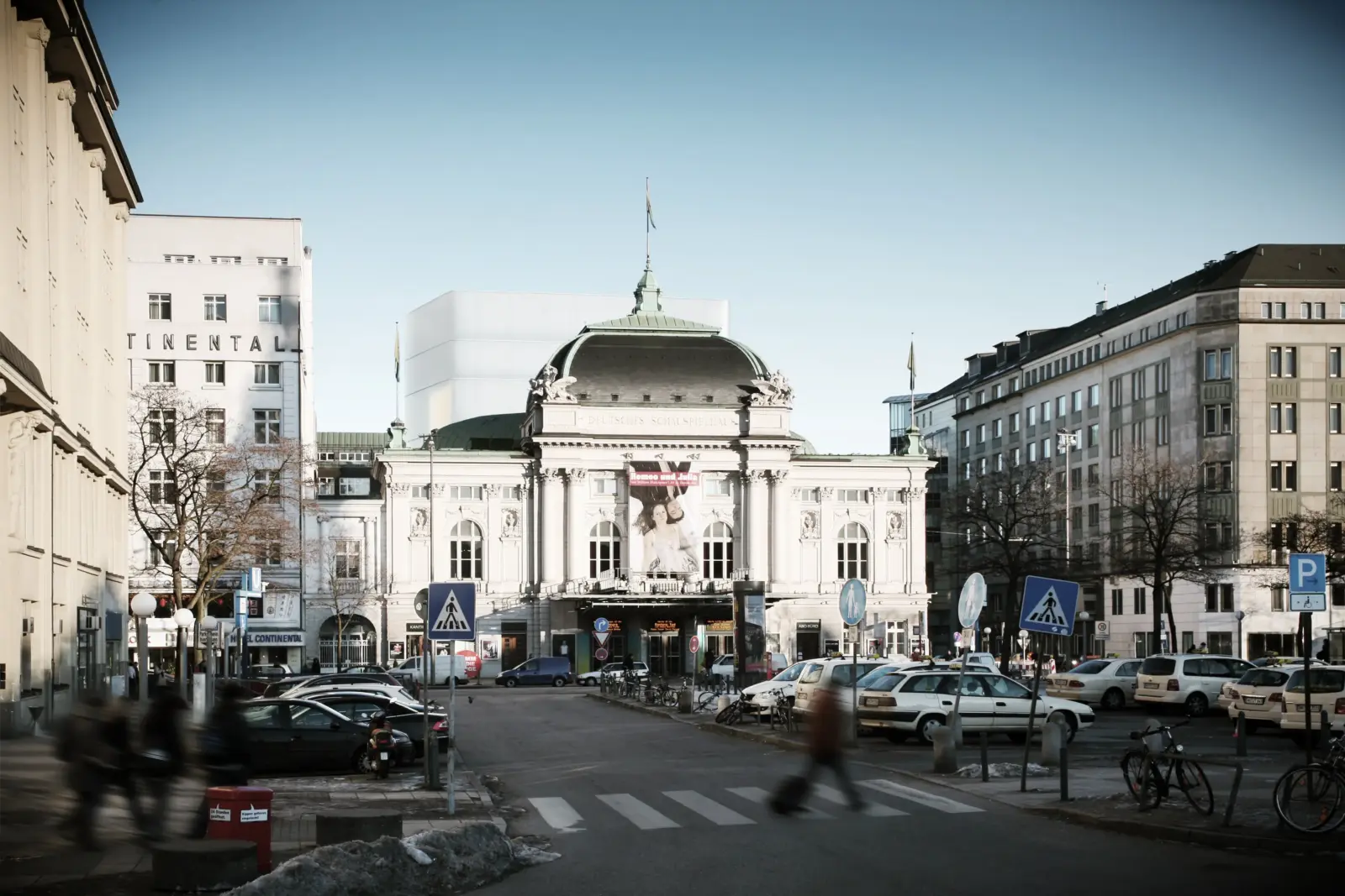 Straßenperspektive mit dem historischen Kuppelbau des Schauspielhauses, hinter dem sich der weiße, kubische Bühnenturm erhebt.
