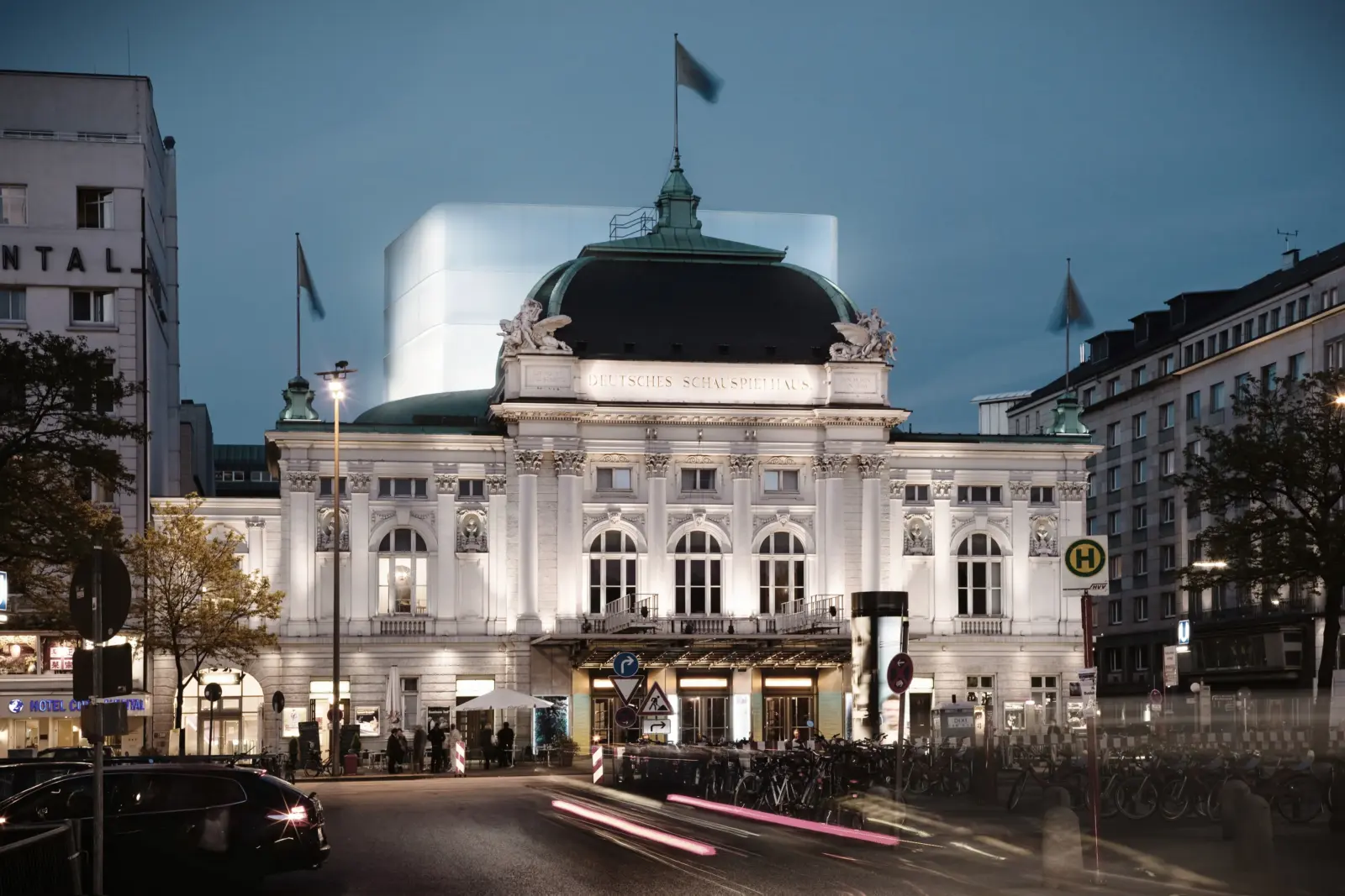 Historisches Theatergebäude mit klassizistischer Fassade, hinter dessen Kuppel ein heller, kubischer Aufbau als neuer Bühnenturm herausragt.