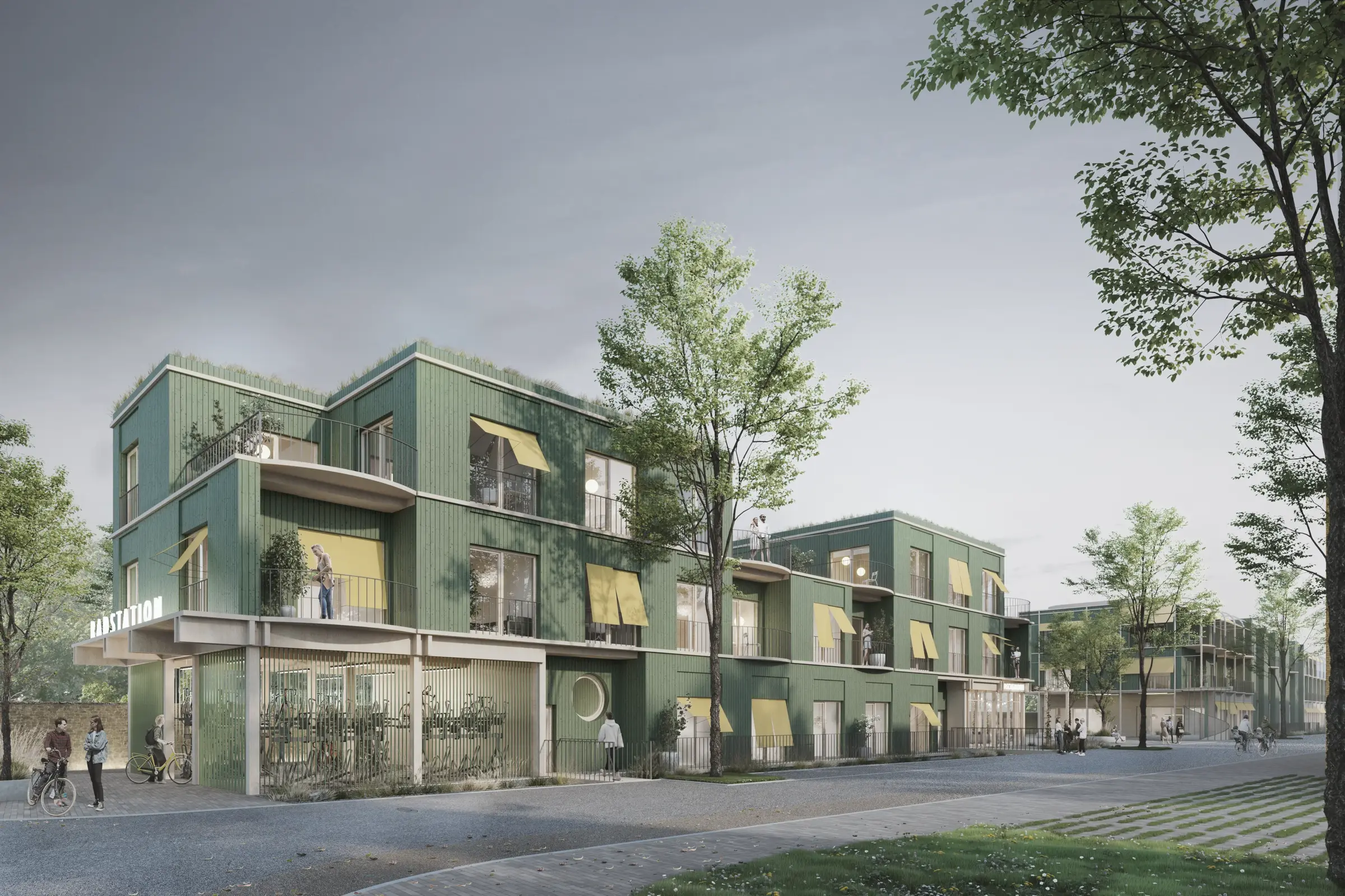 Wohngebäude mit grüner Fassade, begrünten Dachflächen und gelben Markisen, im Erdgeschoss ein überdachter Fahrradabstellplatz mit Radstation.
